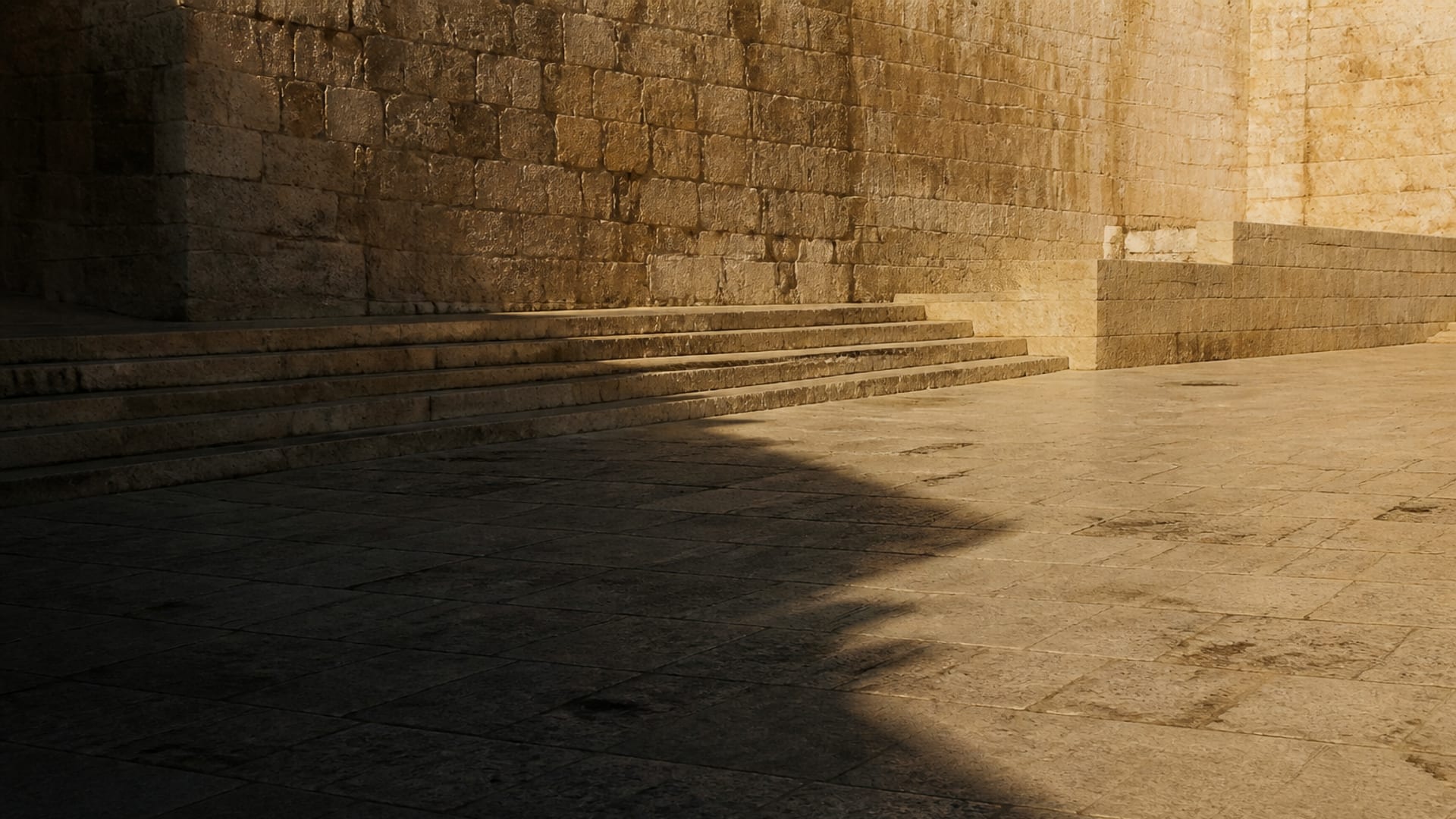 A vast empty paved courtyard with monumental steps, crossed by long shadows in late afternoon light.