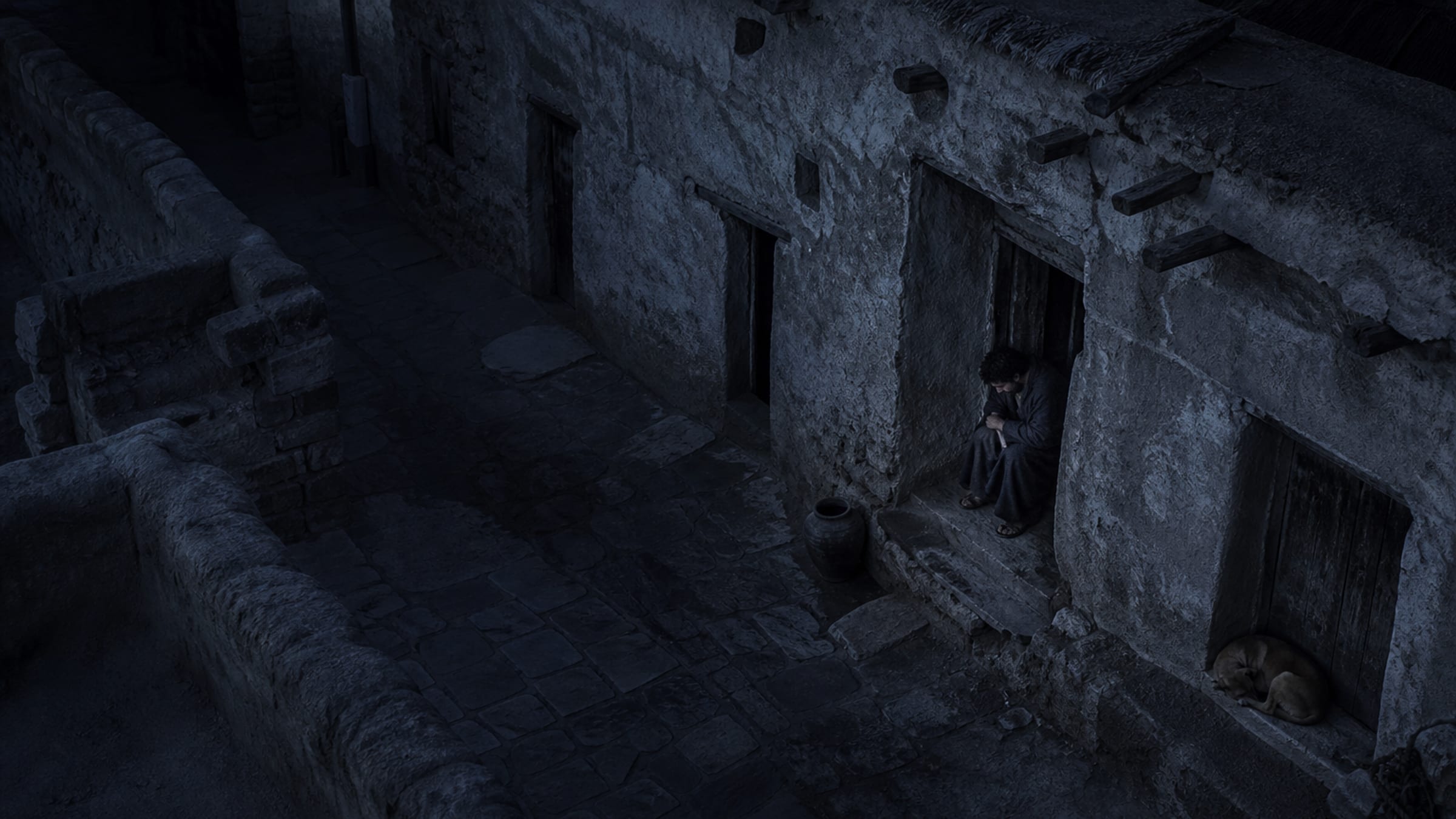 Seen from a rooftop on a moonless night, a lone man presses into a doorway in a narrow ancient alley, yet every stone, jar and door in the street is quietly visible in deep blue light.
